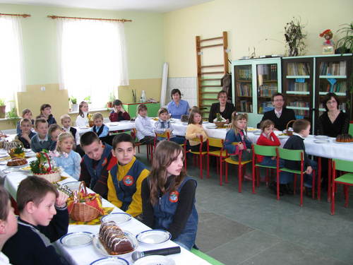 Zasuchani uczniowie i nauczyciele przy wielkanocnym stole.
