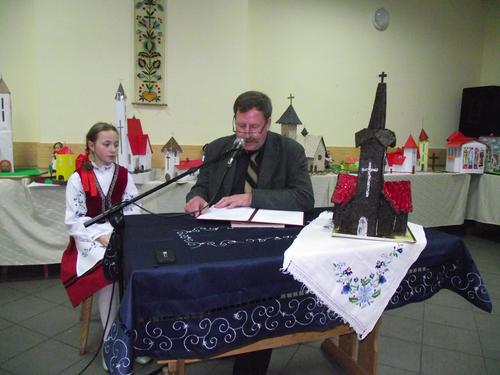 Jan Gadzaa odczytuje legend Marii Kiedrowskiej, na stole nagroda gwna za makiet kocioa - wypiek w ksztacie kocioa