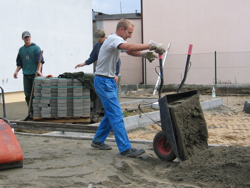 Pracownicy podczas wyrwnywania terenu pod nawierzchni polbrukow.